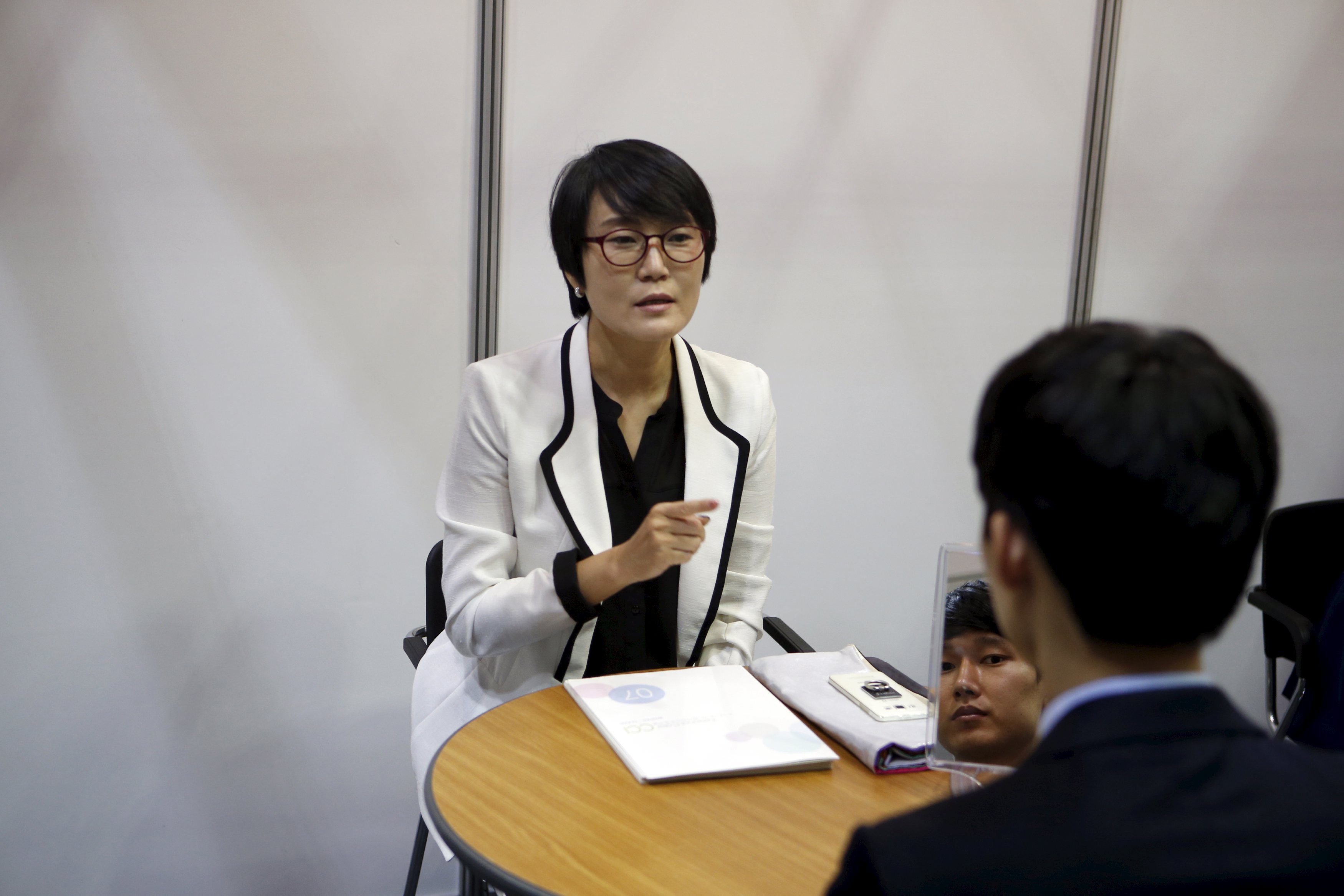 A consultant advises a job seeker at an employment fair in Seoul on Wednesday. | REUTERS