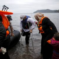 A Syrian refugee amputee exits an overcrowded dinghy Wednesday after crossing part of the Aegean Sea from Turkey to the Greek island of Lesbos. | REUTERS
