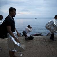 An African migrant prays after he arrived on a inflatable dinghy with others from Turkey on the shores of the Greek island of Lesbos, Wednesday. More than 260,000 asylum-seekers have arrived in Greece so far this year, most reaching the country\'s eastern islands on flimsy rafts or boats from the nearby Turkish coast. | AP
