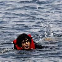 An exhausted Syrian refugee swims toward the Greek island of Lesbos after jumping off an overcrowded dinghy whille crossing part of the Aegean Sea from Turkey to Lesbos on Wednesday. | REUTERS