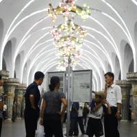 North Koreans read a copy of a daily newspaper displayed on the platform of a subway station in Pyongyang last month. | AP