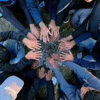 Refugees warm their hands over ashes from a fire at a migrant collection point near the Hungarian village of Roszke, near the border with Serbia, on Tuesday. | AFP-JIJI