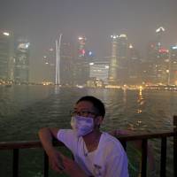 A man watches from a bumboat as he passes the haze-shrouded central business district in Singapore Thursday. The 3-hour Pollutant Standards Index (PSI) reached a hazardous level of 317 at 8 p.m. (1200 GMT) on Thursday. | REUTERS