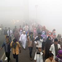 Muslims cover their mouths and noses from the haze from wildfires as they walk to attend a morning prayer marking the Eid al-Adha in Palembang, South Sumatra, Indonesia, Thursday. Slash-and-burn practices destroy huge areas of Indonesian forest every summer during the dry season, creating haze that blankets parts of the archipelago and neighboring Malaysia and Singapore. | AP