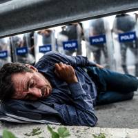 A migrant rests in front of a barricade in Istanbul on Monday after Turkish riot police blocked the road toward Edirne. | AFP-JIJI