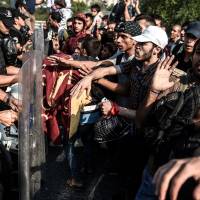 Migrants and refugees try to push a police barricade after they were blocked by Turkish riot police while walking toward Edirne on Monday in Istanbul. A new march by migrants, mainly Syrian, trying to reach Europe overland from Turkey was blocked by police outside Istanbul. The White House vowed more aid for Syrian refugees but Congress may block attempts by the U.S. to take more in. | AFP-JIJI