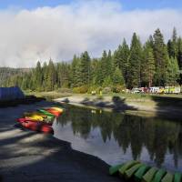 Boats are beached and fire personnel staff Hume Lake in the Sequoia National Forest on Aug. 19 as the Rough Fire continues burning in the background. California\'s largest wildfire burning near the popular Hume Lake in the Central Sierra Nevada raged through the holiday weekend and jumped its containment line Tuesday, prompting evacuations. | ERIC PAUL ZAMORA/THE FRESNO BEE VIA AP