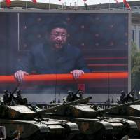 Chinese President Xi Jinping is shown on a big screen as Type 99A2 Chinese battle tanks roll across during a parade in Beijing on Sept. 3 commemorating the 70th anniversary of Japan\'s surrender in World War II. Xi is trying to mend fences across China\'s ideological divide after his crackdown on corruption alienated officials in the Communist Party, government and military. | AP