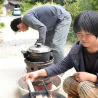 Yuji Shimono prepares the nukakudo cooker, while his wife, Tomoko, prepares the firewood. | CHUNICHI SHIMBUN