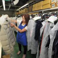 Akemi Hirayama, a single mother who works part-time at Kikuya, checks clothing at a facility in Matsubushi, Saitama Prefecture. | YOSHIAKI MIURA
