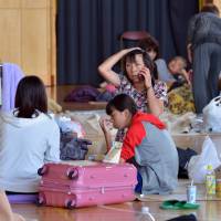 A woman talks on a mobile phone at a shelter in Tsukubamirai, Ibaraki Prefecture, on Friday, a day after an embankment along the Kinugawa River collapsed, flooding the city of Joso. | AFP-JIJI