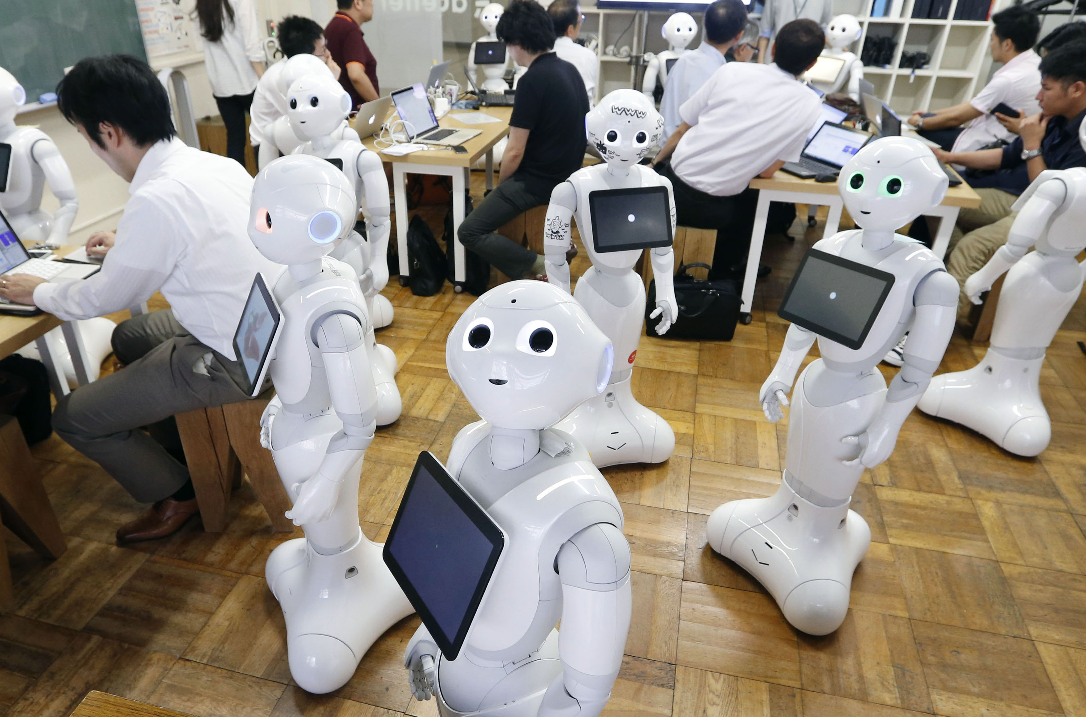 Pepper humanoid robots are shown during a July event in Tokyo. A drunken 60-year-old man was arrested Sunday for allegedly damaging a similar robot in a fit of rage at a SoftBank outlet, police said. | KYODO