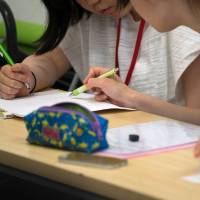 A university student volunteer teaches math to a junior high school student at the Tadazemi free cram school in Tokyo. | BLOOMBERG