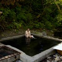 Teacher and journalist Gennadey Berezyuk sits in a hot spring outside Yuzhno-Kurilsk on Kunashiri on Sept. 15. | REUTERS