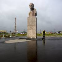 A woman walks past a statue of Soviet founder Vladimir Lenin in Yuzhno-Kurilsk on Kunashiri on Sept. 17. | REUTERS