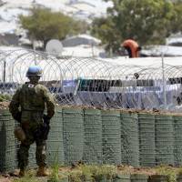A member of the Ground Self-Defense Force guards a fence at a refugee camp in Juba, the capital of South Sudan, on July 24 as part of a U.N. peacekeeping operation. | KYODO