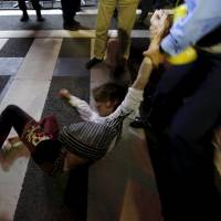 A protester falls as a police officer holds his arm during a rally against Japan\'s Prime Minister Shinzo Abe\'s security bill and his administration in front of the parliament in Tokyo on Tuesday. Three protestors were eventually arrested. | REUTERS