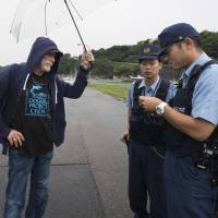 Animal rights activist Ric O\'Barry speaks with police officers patrolling the harbor at Taiji, Wakayama Prefecture, on Sept. 9. | ROB GILHOOLY