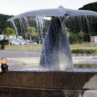 A man and his daughter play with water from a fountain outside the whaling museum in Taiji, Wakayama Prefecture, on Sept. 10, 2009. | ROBERT GILHOOLY