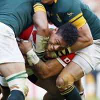 Three South African players try to bring down Japan\'s Amanaki Lelei Mafi during their game on Saturday. | KYODO