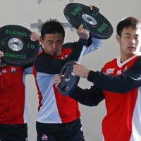 Japan\'s Ayumu Goromaru (center) and two teammates work out with weights on Tuesday in Warwick, England. | REUTERS