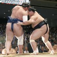 Ozeki Terunofuji (right) forces komusubi Tochinoshin out of the raised ring on Friday at the Autumn Grand Sumo Tournament. | KYODO