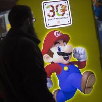 A visitor walks past a Super Mario logo at a Nintendo Co. stand at the EGX 2015 video game conference in Birmingham, England, in September. Nintendo has been dropped for the first time from U.S.-based Interbrand\'s list of the top 100 global brands. | BLOOMBERG