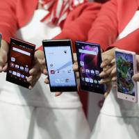 Staff display new NTT Docomo Inc. smartphones at a launch in Tokyo on Sept. 30. Under a new tie-up, visitors to Docomo stores will be able to buy Nippon Life Insurance Co. policies. | BLOOMBERG