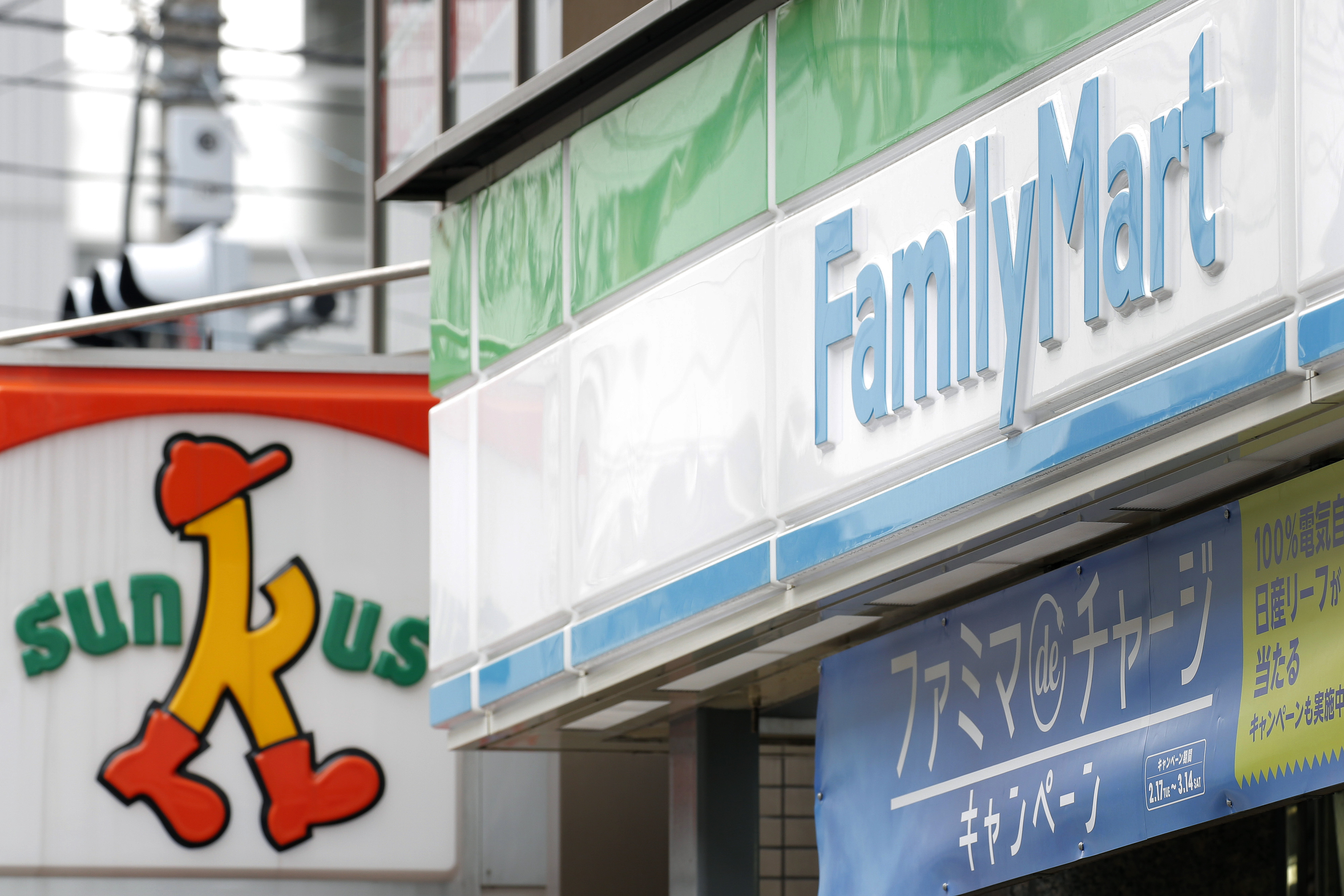 Signs for FamilyMart Co. and Sunkus convenience stores are displayed in Tokyo in March. The operator of Sunkus is Uny Group Holdings Co. | BLOOMBERG