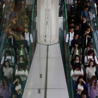 People ride on an escalator in Tokyo. Job availability continued to improve for the third straight month in September to hit the highest level in over 23 years. | BLOOMBERG