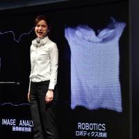 A model demonstrates a prototype of an automatic laundry-folding machine called \"Laundroid\" during CEATEC, Asia\'s largest electronics trade show, in Chiba Prefecture Wednesday. | AFP-JIJI