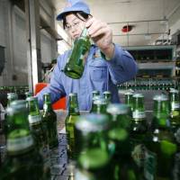 A worker checks beer labels at a bottling line at the Tsingtao Brewery in Qingdao, Shandong province, in 2006. | QILAI SHEN