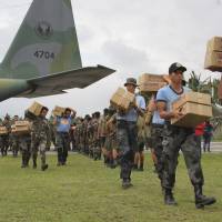 Philippine troops unload a military plane carrying relief aid at an airport in Baler province, in the northern Philippines on Wednesday. Typhoon Koppu left several people dead and forced more than 100,000 villagers into emergency shelters. It also destroyed rice crops ready for harvest. | AP