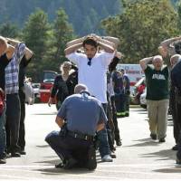 Police search students outside Umpqua Community College in Roseburg, Oregon, Thursday following a deadly shooting at the college. | MIKE SULLIVAN / ROSEBURG NEWS-REVIEW VIA AP