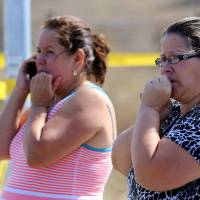 Two woman wait outside Umpqua Community College campus after a shooting at the school in Roseburg, Oregon, on Thursday. | AP