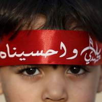 A Saudi Shiite boy wearing headband that reads \"Oh Hussein\" takes part in an Ashura procession in Qatif, Saudi Arabia, on Saturday. Ashura, which falls on the 10th day of the Islamic month of Muharram, commemorates the death of Imam Hussein, grandson of the Prophet Muhammad. Hussein was killed in the 7th century battle of Karbala. | REUTERS