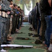 Armed men pray inside a mosque in Salah al-Din neighborhood of Aleppo, Syria, on Friday. | REUTERS