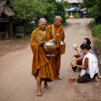 Buddhist monks receive rice from women in a village outside Nong Khai, Thailand on Sept. 16. The rural heartland of Thailand\'s deposed leader Yingluck Shinawatra and her exiled billionaire brother Thaksin is hurting as a result of the military government\'s economic policies, stirring discontent and the threat of protests. | REUTERS