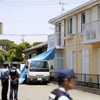 Police officers in June 2014 inspect the apartment building where Riku Saito\'s skeletal remains were found some seven years after the 5-year-old died of malnutrition in a room where he was locked up by his father. | KYODO