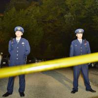 Police officers stand guard in the area where a 10-year-old boy\'s body was found in Hino, Tokyo, on Monday night. | KYODO