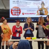 Yokohama resident Tomoko Fujimoto (second from left) shows visitors to the Japan Pavilion how to make a misomaru (a roll of fermented soybean paste with filling), at Expo Milano 2015 in May. Visitors were able to sample miso soup made from the roll. | KYODO
