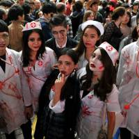 A group of Halloween revelers dressed as zombie hospital staff pose for a photo Saturday evening in Hachiko Square in front of JR Shibuya Station in Tokyo. | YOSHIAKI MIURA