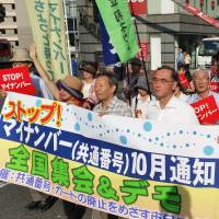 People opposed to the My Number identification card system march through the streets of the Shibuya district in Tokyo on Saturday. | TOMOHIRO OSAKI