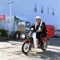 A postman leaves a post office in Aomori on a motor bike Friday morning to deliver identification numbers to residents under the new My Number system. | KYODO