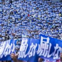 People hold signs saying \"don\'t give in\" during a rally in Naha on May 17 over the planned relocation of U.S. Marine Corps Air Station Futenma to Henoko. | ARI HATSUZAWA