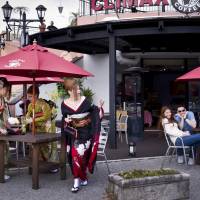 Young women attending a coming-of-age ceremony chat at a cafe in Chatan while a woman and an American man enjoy themselves at a nearby table. | ARI HATSUZAWA