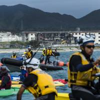 Coast Guard personnel block protesters off Henoko Bay in May. Barracks are being dismantled at Camp Schwab, and residents worry that the debris might end up in landfill. | ARI HATSUZAWA