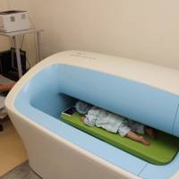 An employee at Hirata Central Hospital in Fukushima Prefecture gauges a baby\'s internal radiation exposure using a new advanced scanner in this undated photo. | HIRATA CENTRAL HOSPITAL