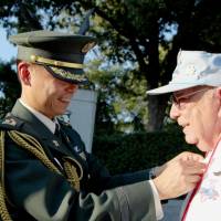 Masashi Yamamoto, a Ground Self-Defense Force colonel, awards a Japanese paratrooper\'s badge to U.S. veteran William LaRou on Wednesday at Arlington Cemetery in Virginia. | KYODO