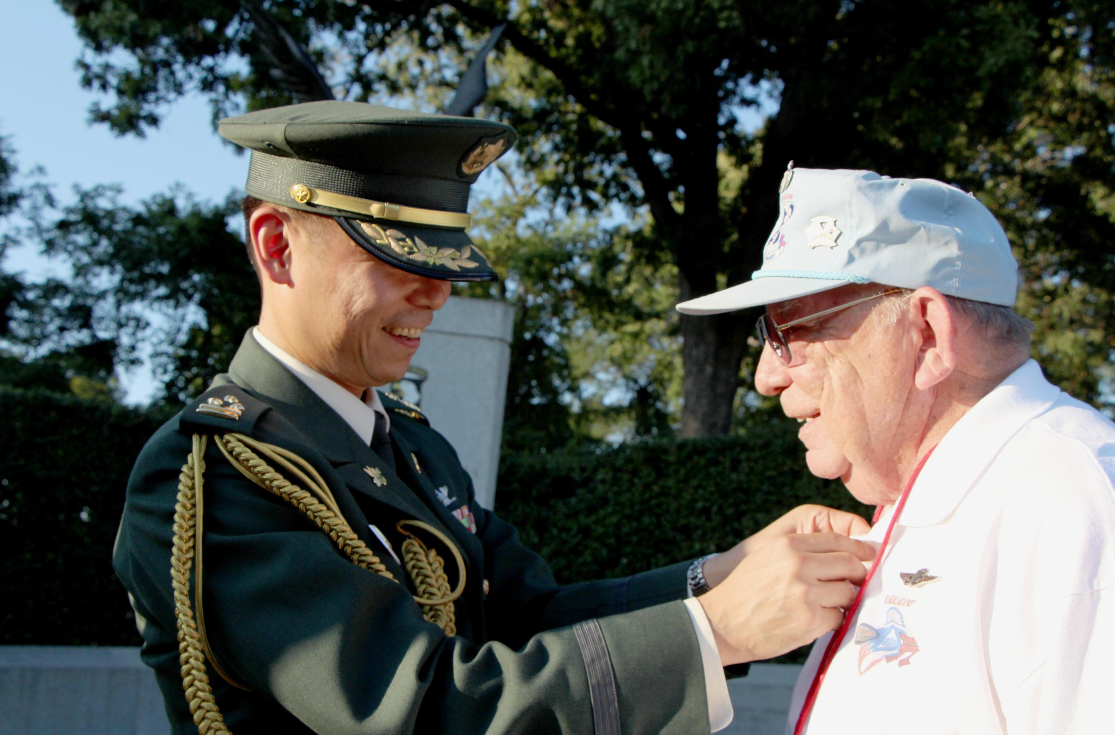 Masashi Yamamoto, a Ground Self-Defense Force colonel, awards a Japanese paratrooper's badge to U.S. veteran William LaRou on Wednesday at Arlington Cemetery in Virginia. | KYODO